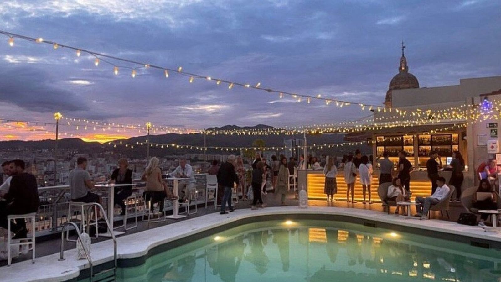 Rooftop bar in Málaga met uitzicht op kathedraal en haven in de avond | MDR Luxury Homes Rooftop bar in Málaga met uitzicht op kathedraal en haven in de avond